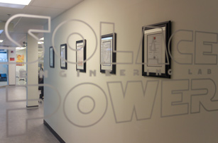 Solace Power Engineering Lab printed on a clear glass door looking into a room with framed certificates on the wall.