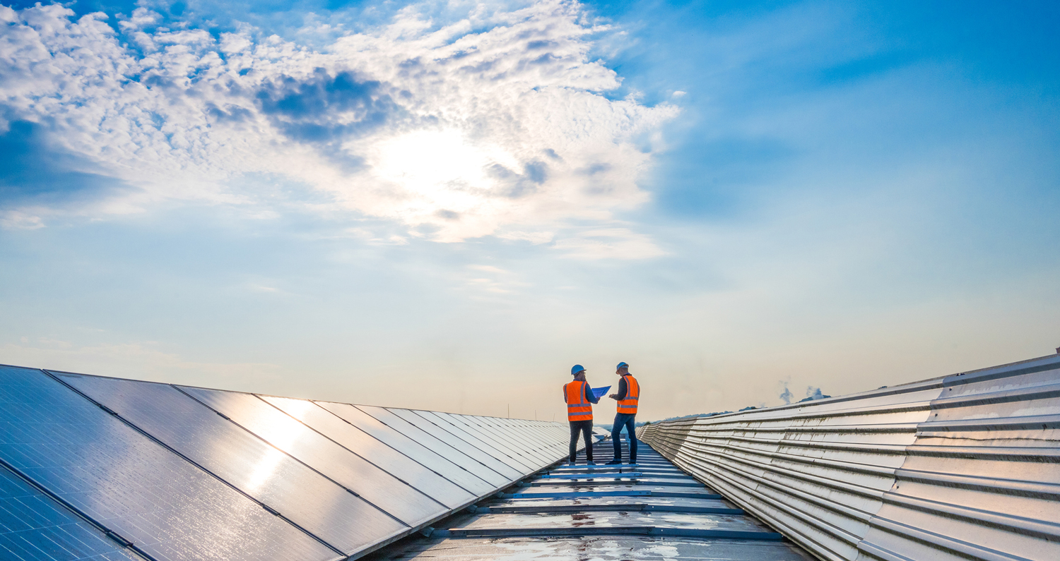 Two technicians in distance discussing between long rows of photovoltaic solar panels