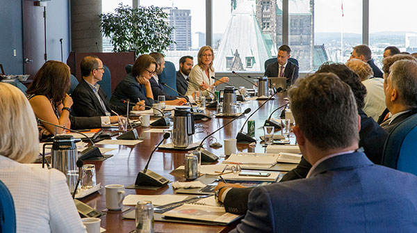 Wide-angle photo of people around a boardroom table at an innovation round-table discussion on positioning Canada as a global centre of innovation